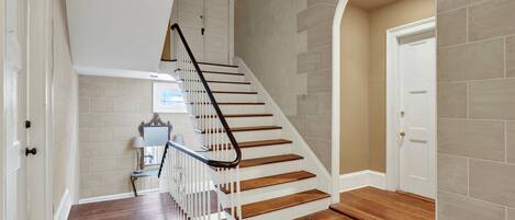 A staircase with wooden steps and a metal handrail, leading to a door with a white frame.