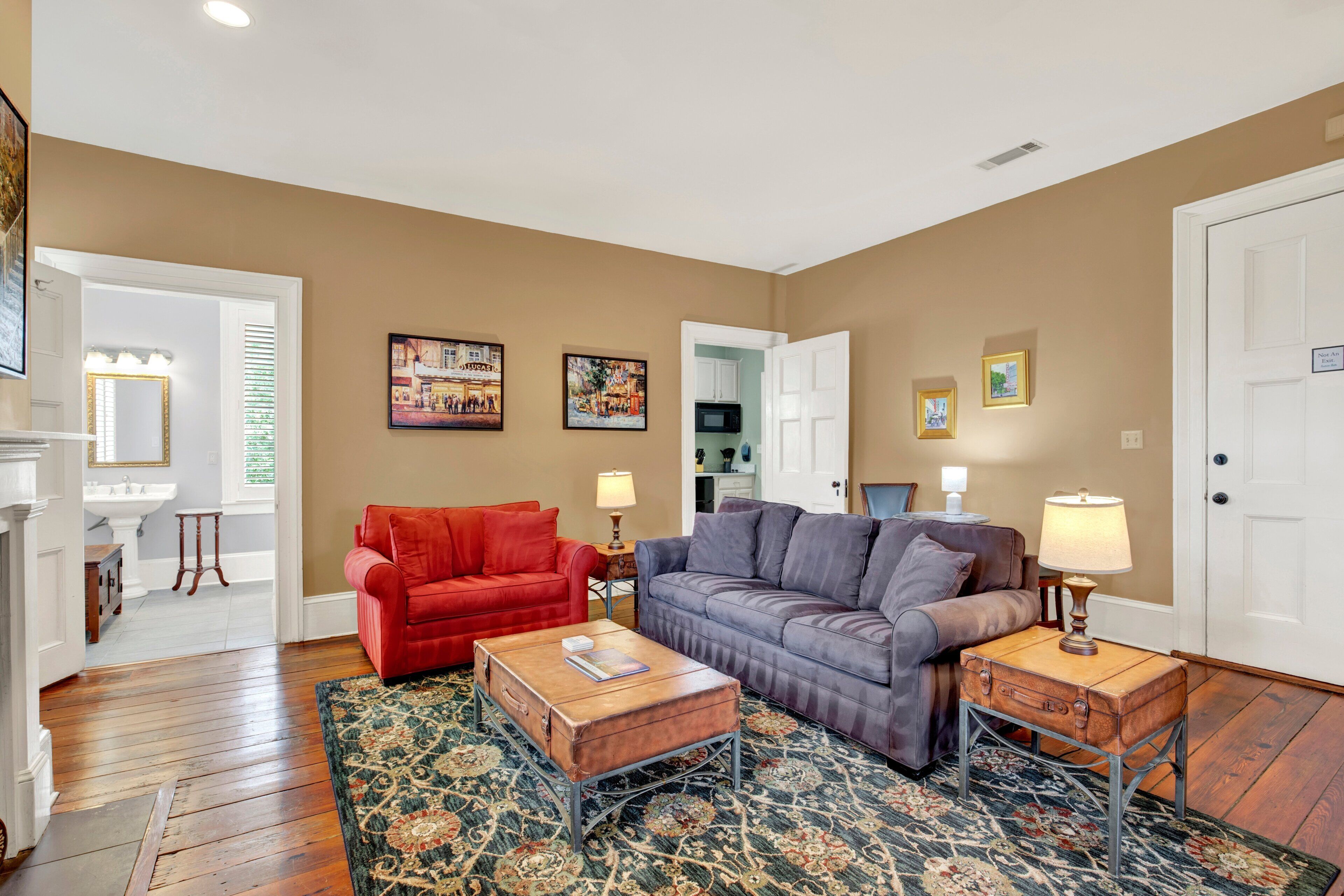 A living room with a red sofa, a gray sofa, a wooden coffee table, and a patterned rug.