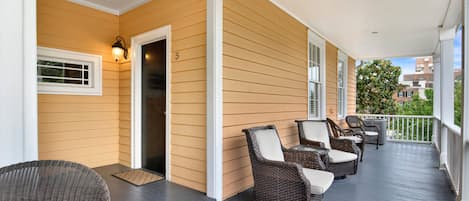 A covered porch with wicker furniture, a door, and a window.