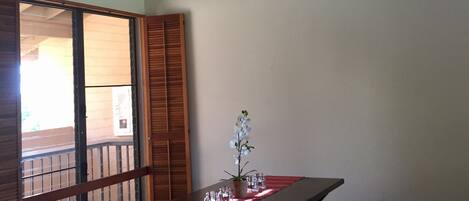 Un espace repas comprenant une table, des bancs, un ventilateur de plafond et une vue à travers une porte coulissante.