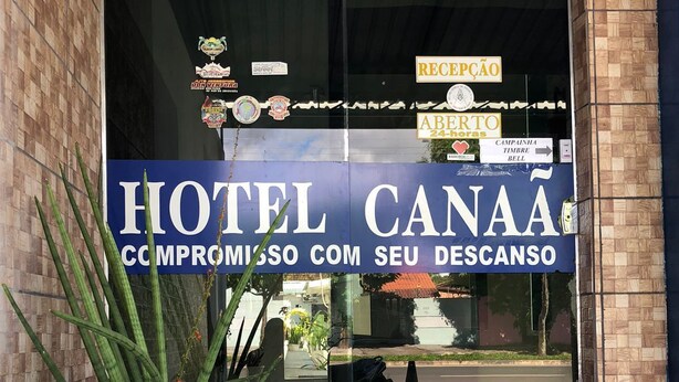 En hotelindgang med et stort skilt, hvor der står "HOTEL CANAA", og et mindre skilt nedenunder med teksten "COMPROMISSO COM SEU DESCANSO".