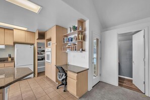 Una cocina compacta con electrodomésticos integrados, un comedor pequeño y un vestidor.