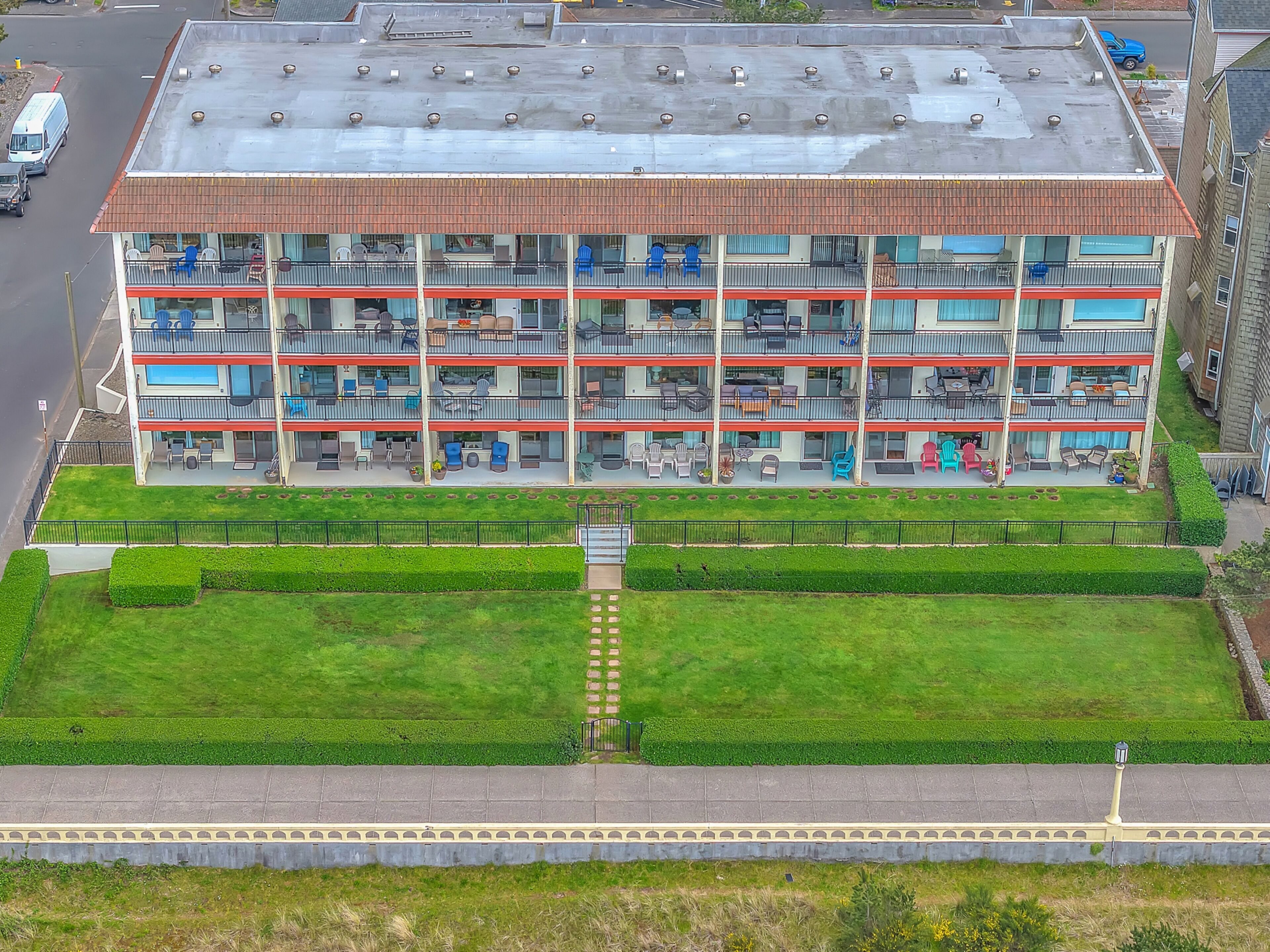 A multi-story building with balconies, outdoor seating, and a well-maintained lawn.