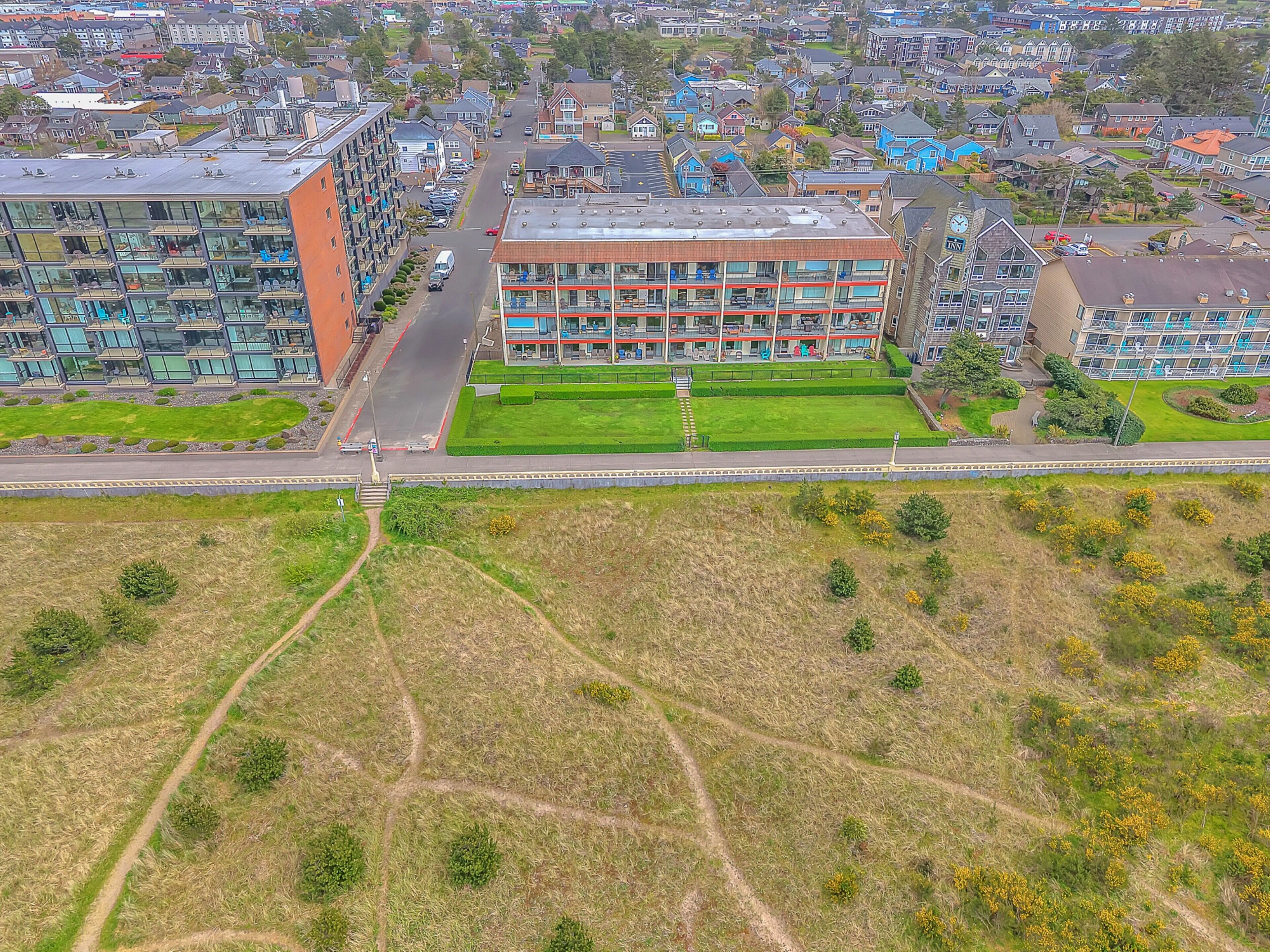 Vue aérienne d’un quartier résidentiel avec des immeubles d’appartements modernes, un espace vert central et une route.