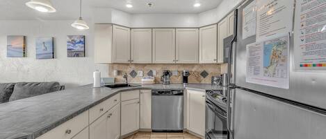 Una cocina moderna con armarios blancos, electrodomésticos de acero inoxidable y un salpicadero de azulejos.