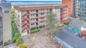 Un edificio a più piani con balconi, un parcheggio e vista sull'oceano.