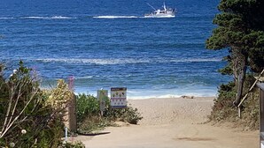 Une plage avec un bateau sur l’eau et un panneau indicateur au premier plan.
