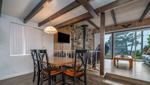 Un coin repas avec une table et des chaises en bois, un mur en pierre et un téléviseur fixé au mur.