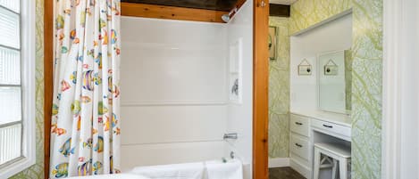 Une salle de bain avec une baignoire, un rideau de douche et un meuble-lavabo avec un miroir.