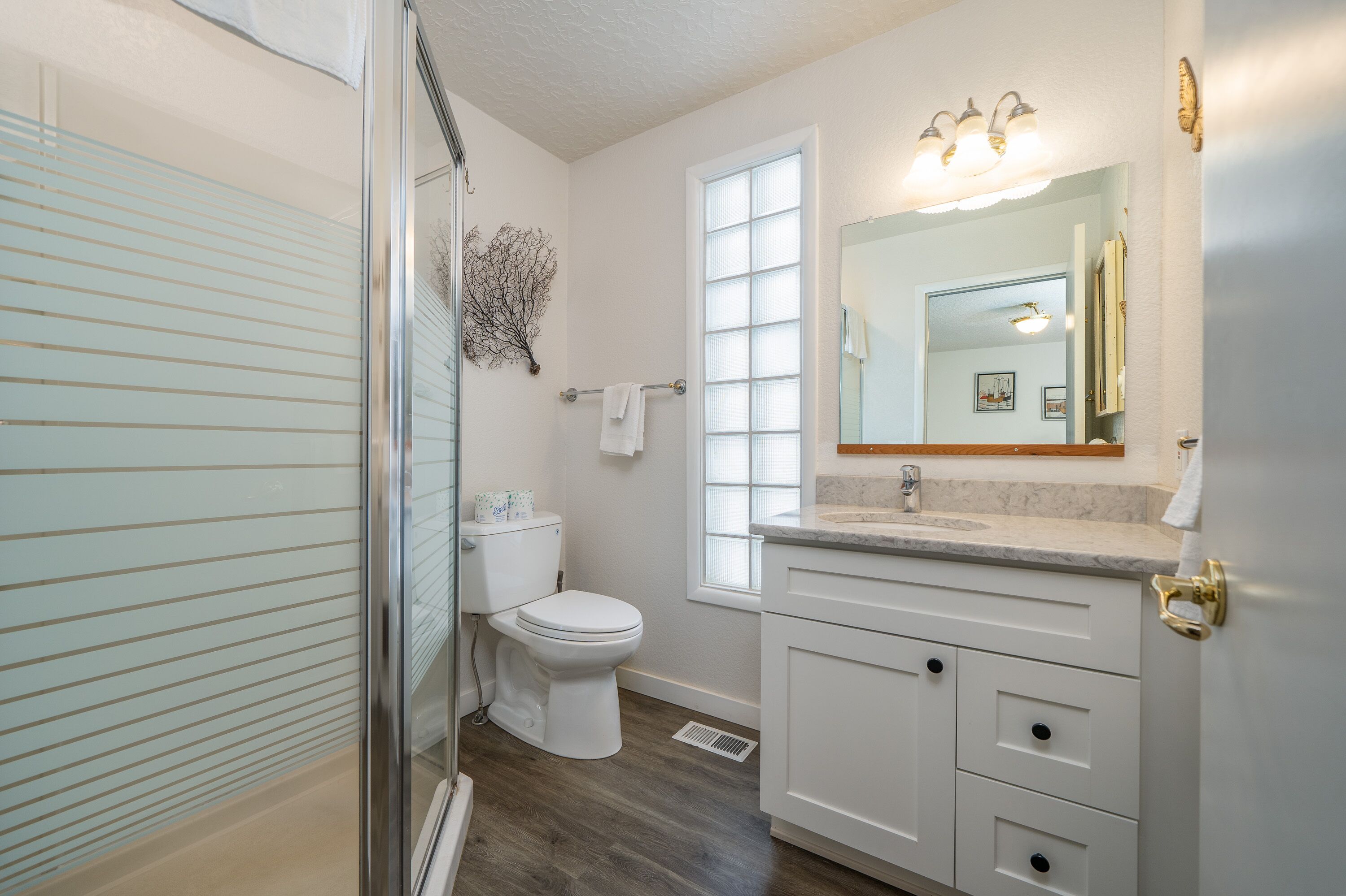 Une salle de bain avec une douche à parois de verre, des toilettes, un lavabo avec un meuble-vasque et un grand miroir.