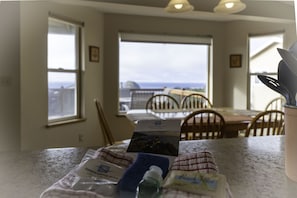 Une cuisine avec vue sur l’océan, une table à manger, des chaises et un comptoir sur lequel sont disposés divers objets.