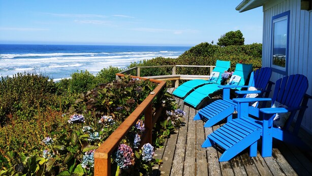 A wooden deck with blue Adirondack chairs and a view of the ocean. - Oceanfront Cottage with Deck and Ocean Views, Dogs Ok, Perfect Couples Retreat (Seal Rock)