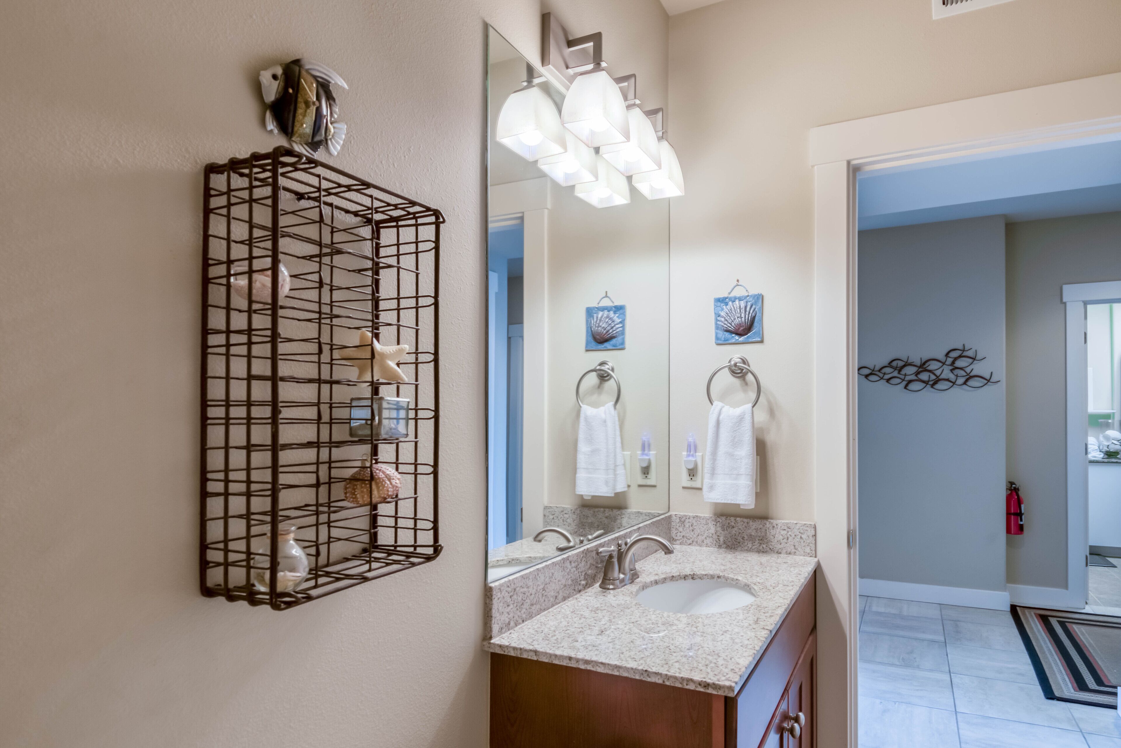 A bathroom with a large mirror, a sink, and a towel rack.
