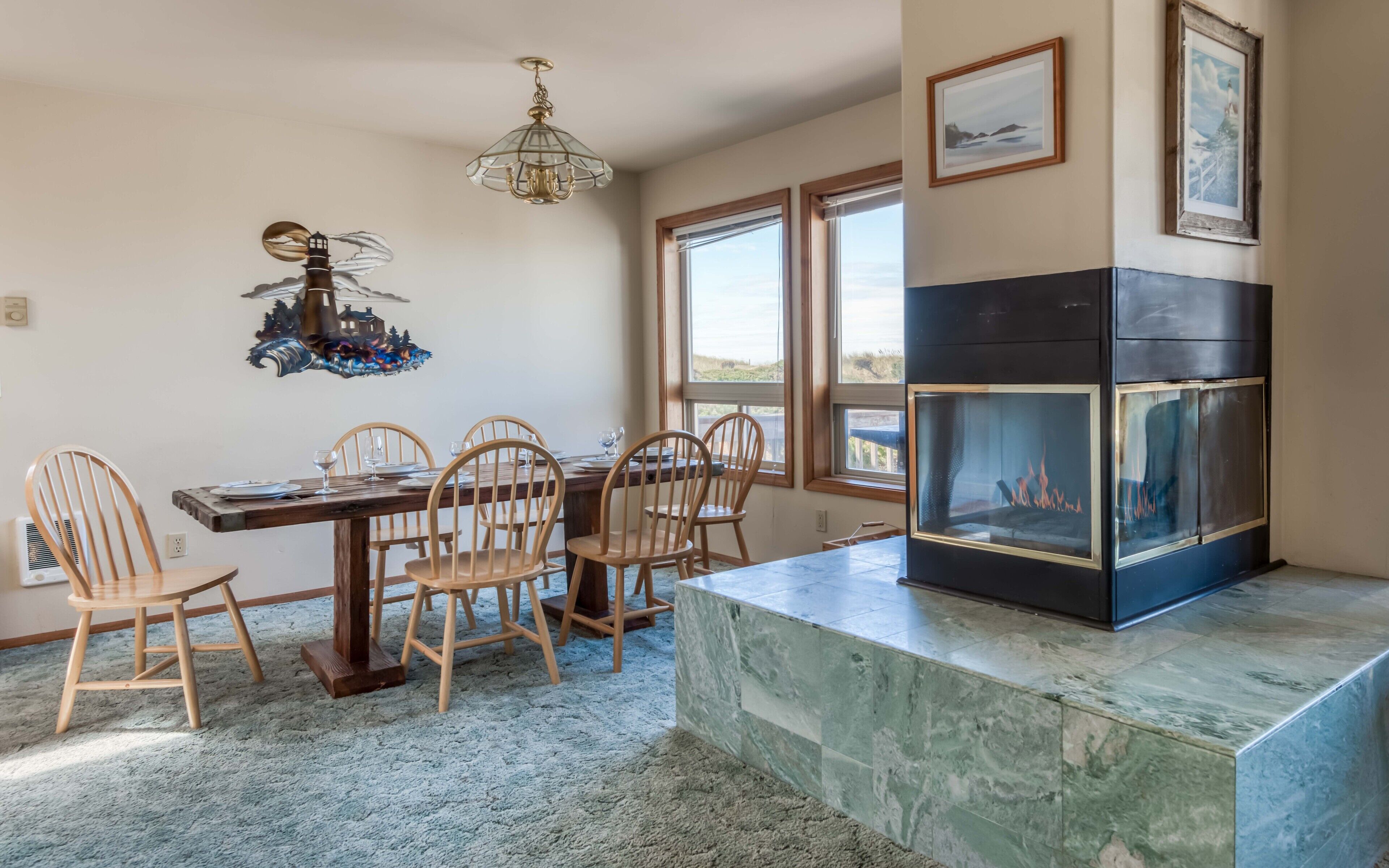 A dining area with a wooden table, chairs, a chandelier, and a fireplace.