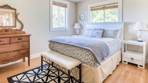 Een slaapkamer met een bed, een bankje, een dressoir en twee nachtkastjes.