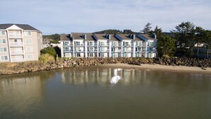 Ein Hotel am Wasser mit mehreren Balkonen und einer Steinmauer entlang der Uferlinie.