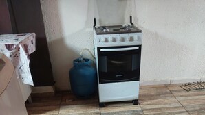 A kitchen with a gas stove, oven, and a blue gas cylinder.