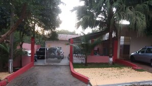 A gated entrance with a paved driveway leading to a building with a red and white facade.