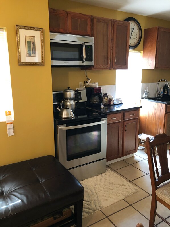 A kitchen with wooden cabinets, a stainless steel stove, a microwave, and a coffee maker. - Wonderful Home located on Highway 90 outside of Quincy (Quincy)