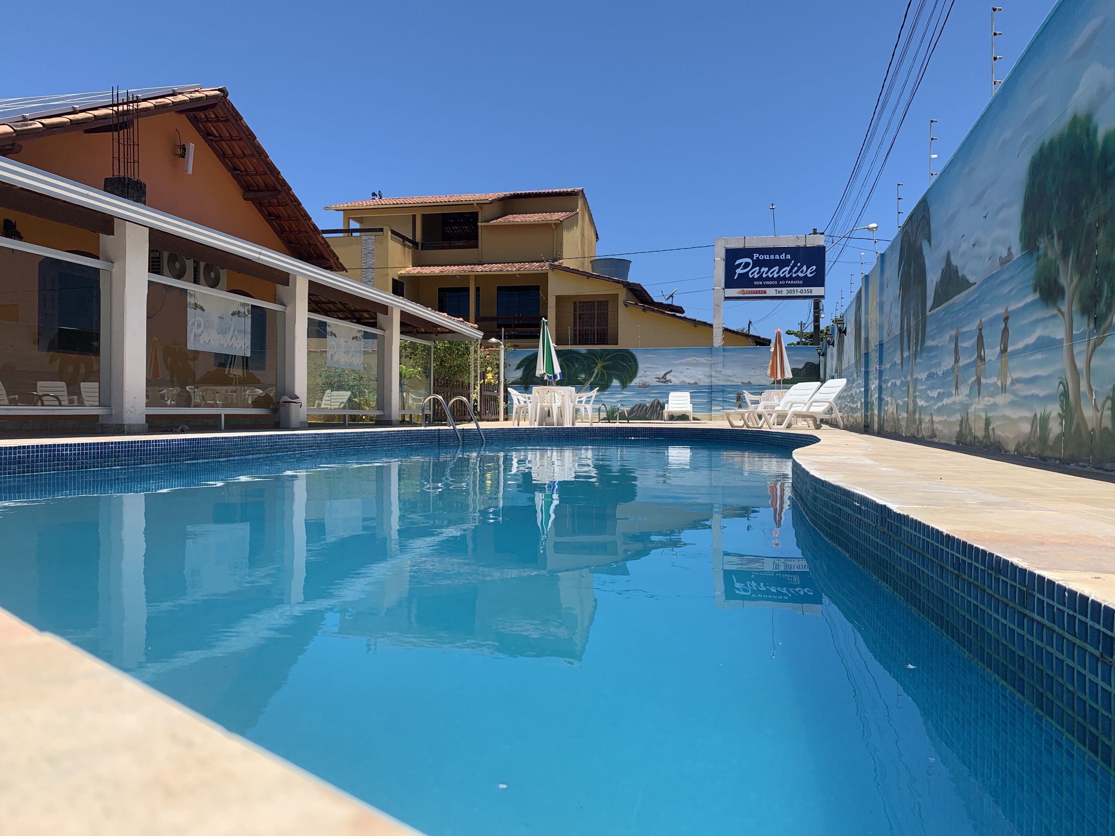 A swimming pool with lounge chairs and a mural on the wall.