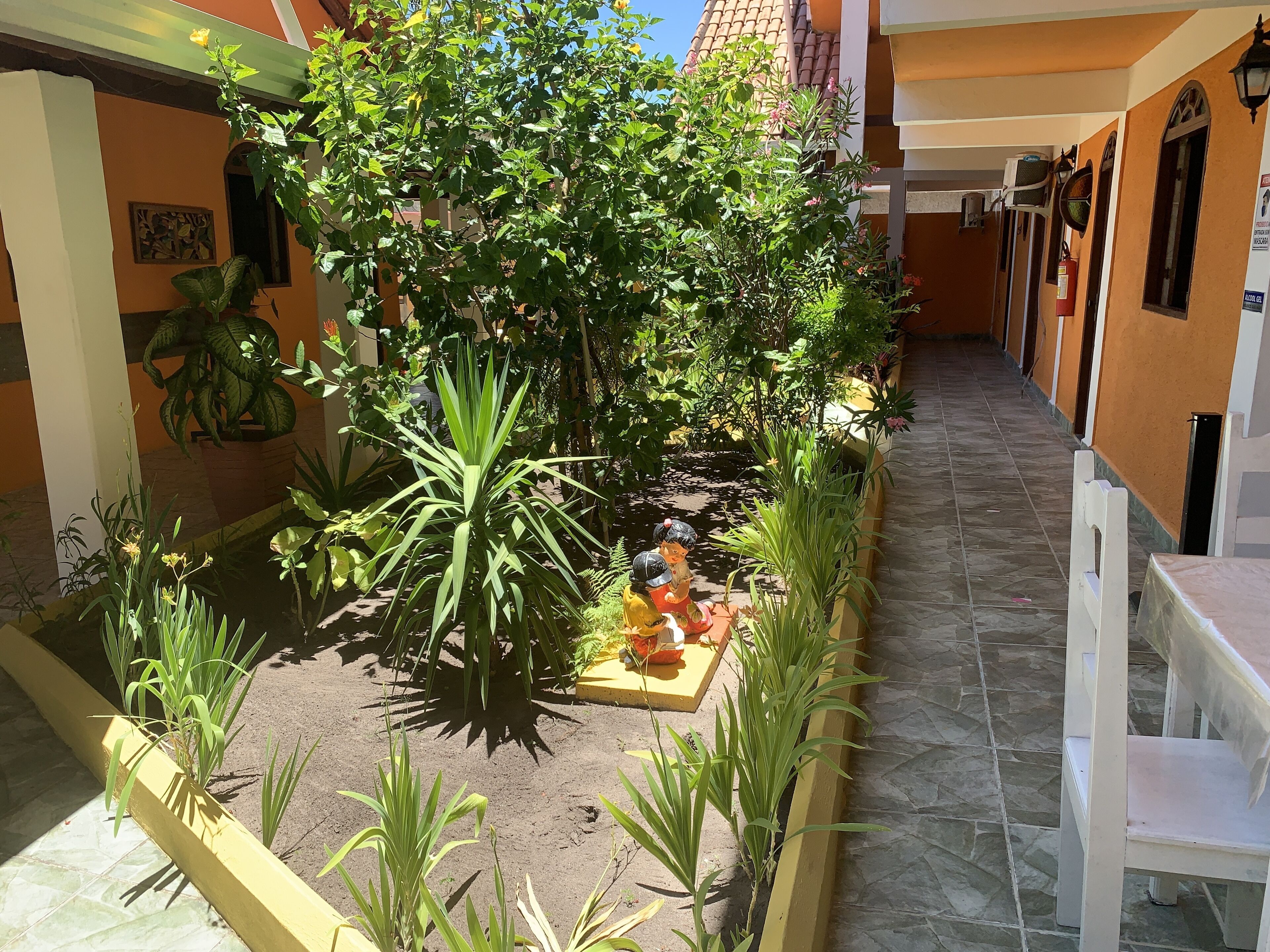 Un patio con un pequeño estanque, rodeado de diversas plantas y una estatua.