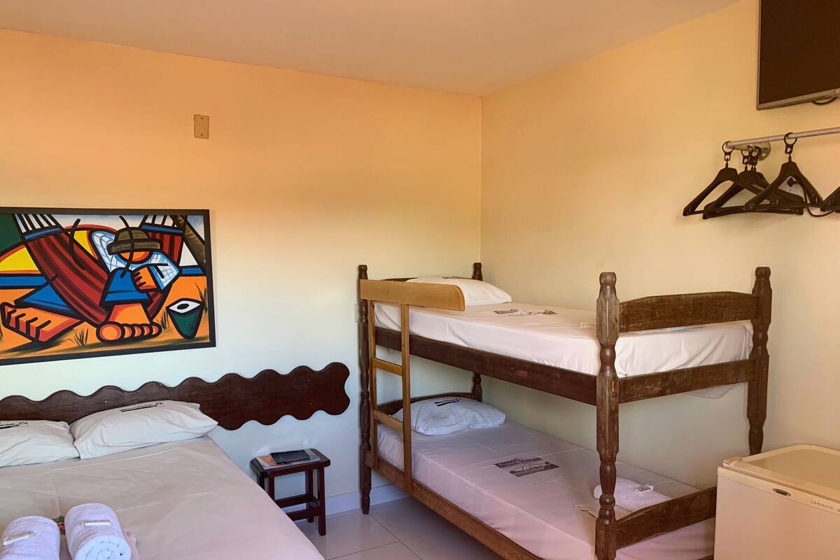 A room with two bunk beds, a small table, a wall-mounted TV, and a painting.
