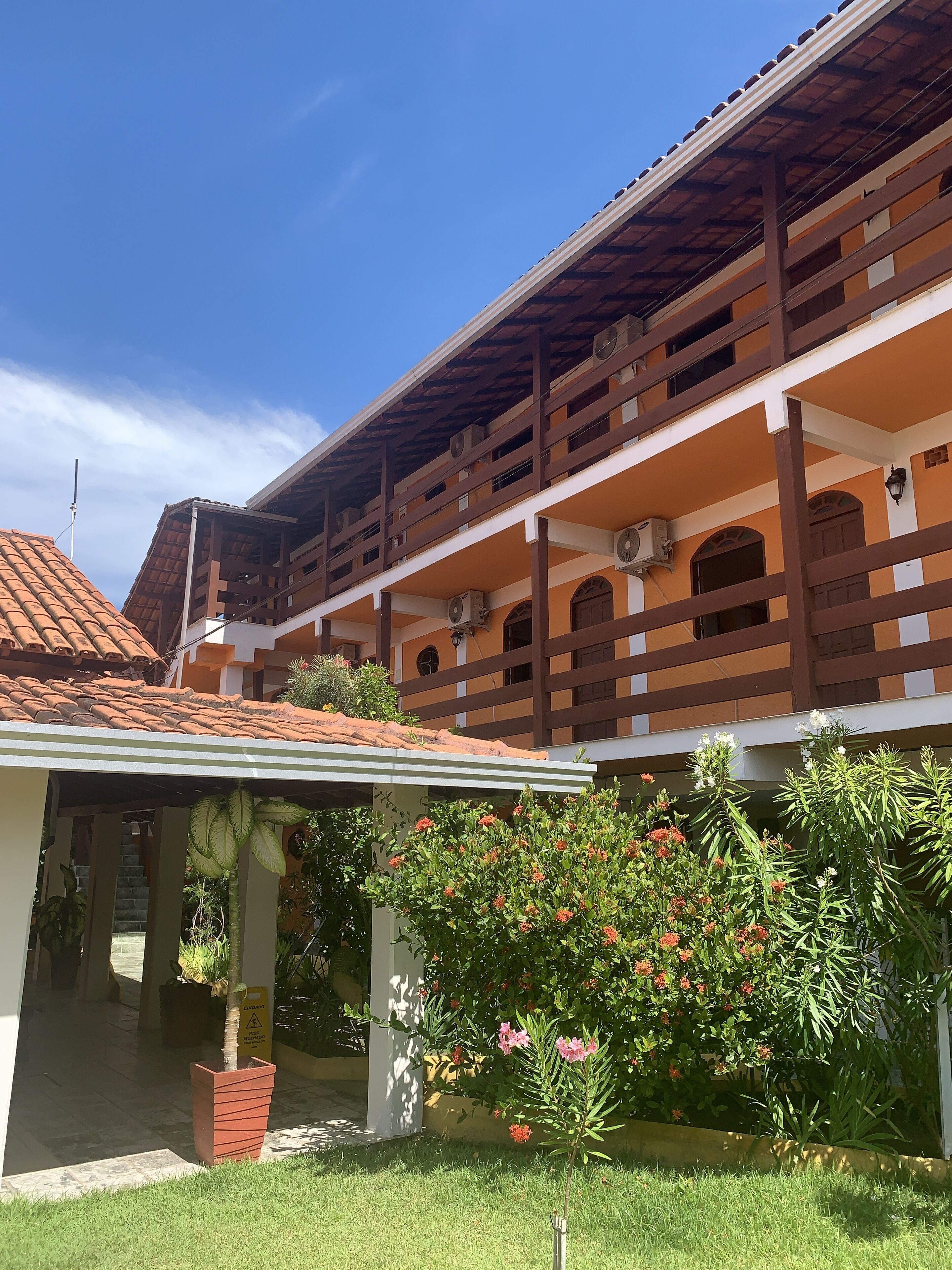 A two-story building with a tiled roof, balconies, and a covered entrance.