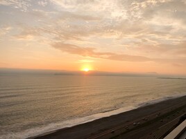 Un atardecer sobre una carretera costera con una playa y el océano.