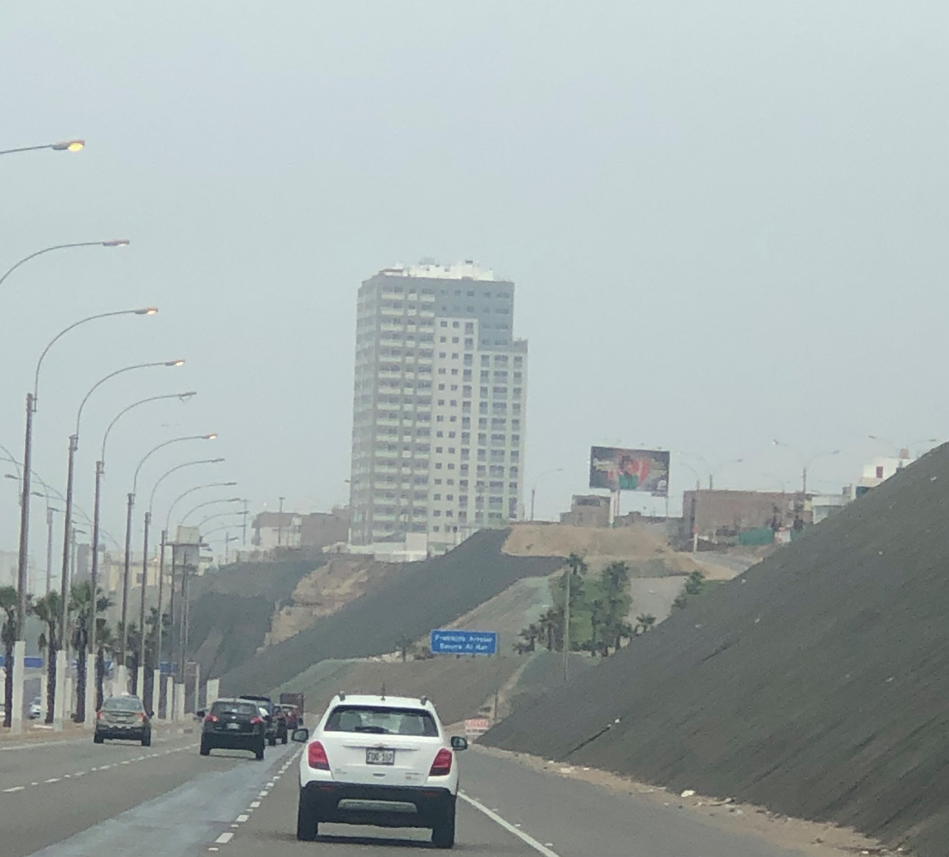 A highway with multiple lanes, cars, streetlights, and a large building in the background.