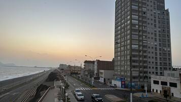 A coastal road with a high-rise building, a pedestrian walkway, and a view of the sea.