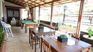 An outdoor patio with a pool table, wooden tables, and chairs. - Ubaense Plaza Hotel (Uba)