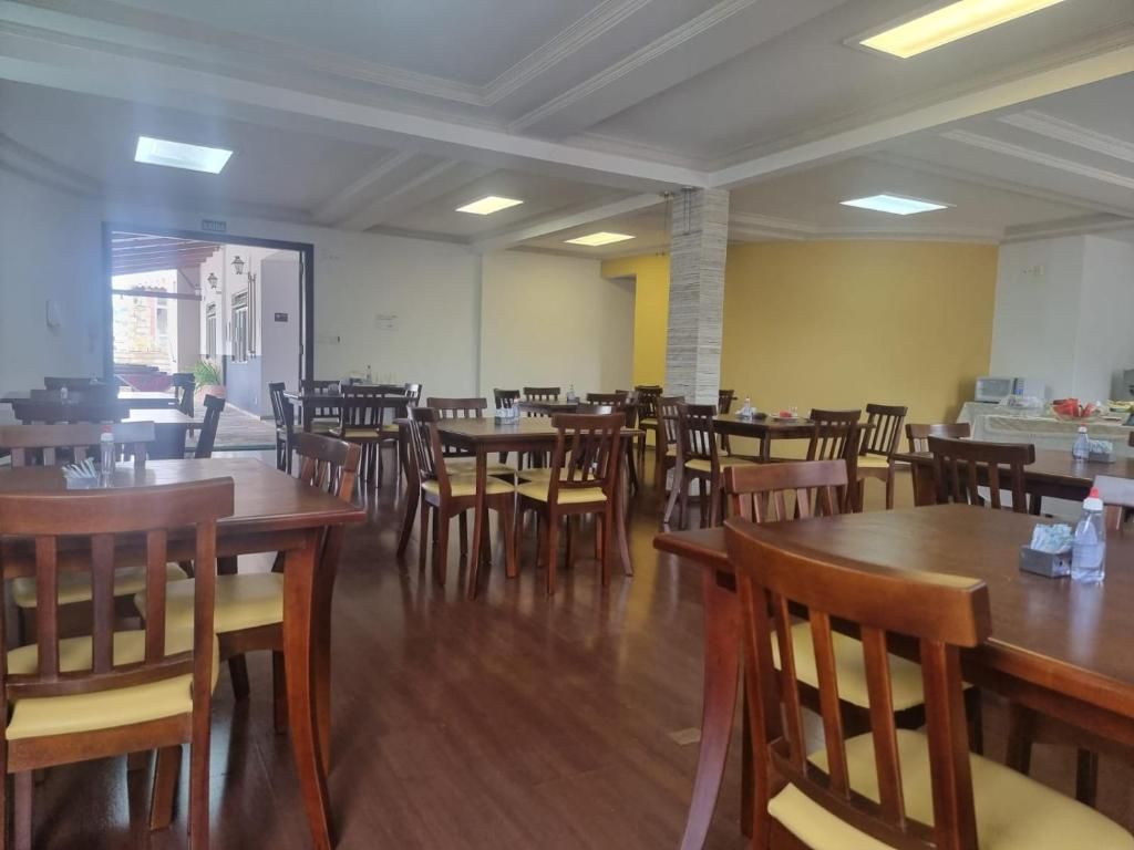 A dining area with multiple wooden tables and chairs, a stone pillar, and a view of the outside.