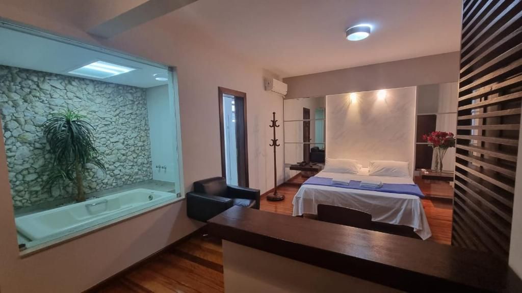 A modern bedroom with a large bed, a sitting area with a chair, a small table, and a large window.