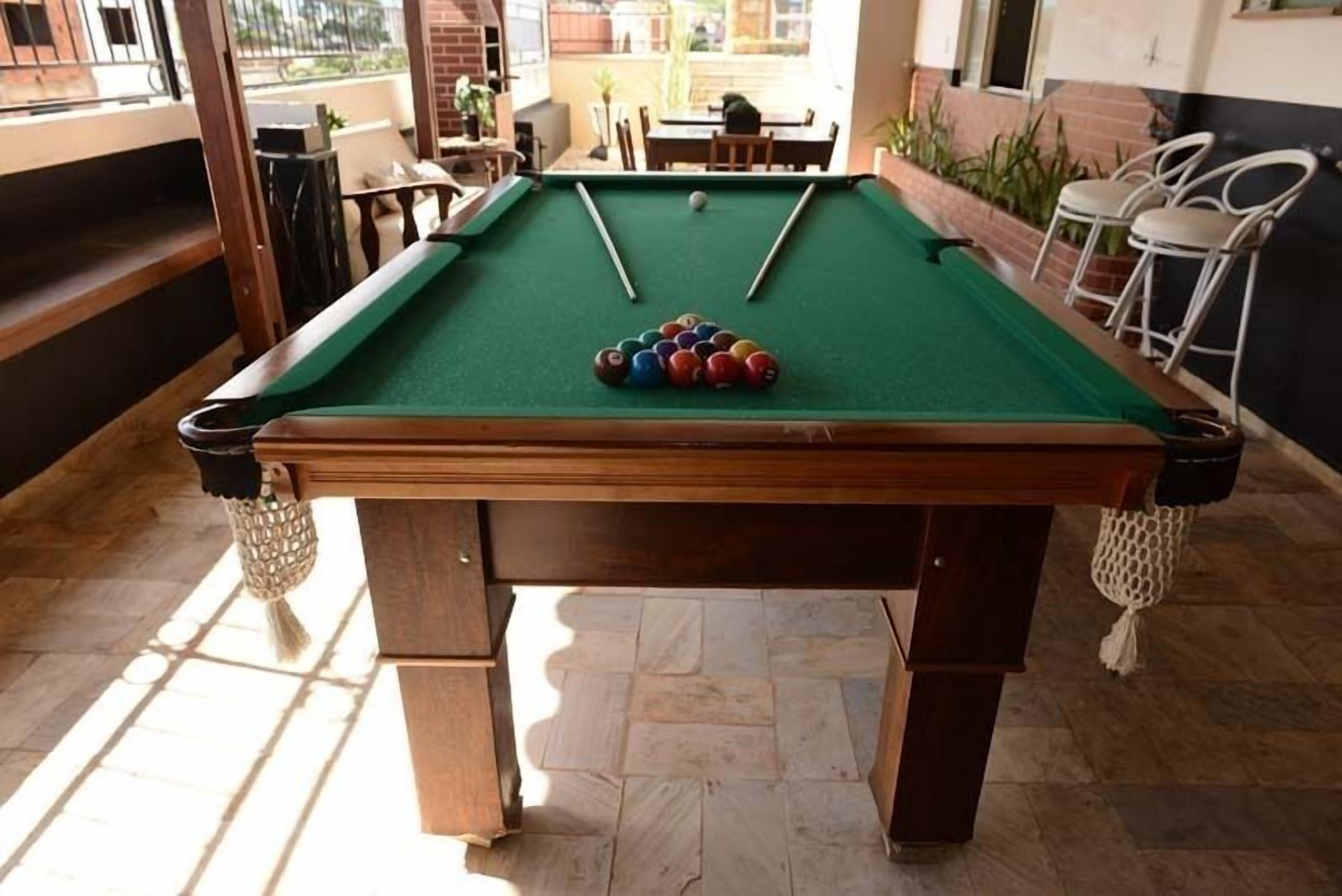 A pool table with balls in the center, surrounded by chairs and tables in a well-lit indoor area.