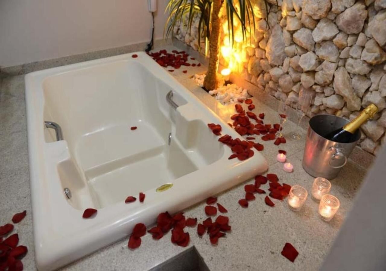 A bathtub with rose petals and candles, suggesting a romantic setting.