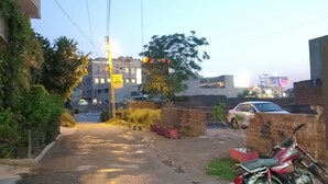 A building with a sign indicating it is a hotel. There is a parked car and a motorcycle in the foreground. - Family Hotel Lahore  (Block R 2)