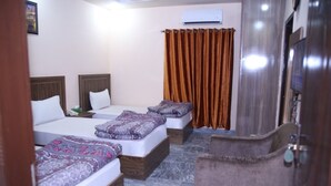 A hotel room with two beds, a wooden headboard, a grey carpet, and a brown curtain. - Family Hotel Lahore  (Block R 2)