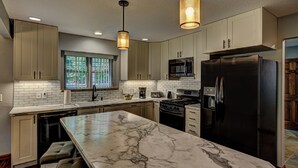 Una cocina moderna con encimeras de mármol, electrodomésticos de acero inoxidable e iluminación colgante.