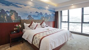 A hotel room with a large bed, a nightstand with a vase of flowers, a mural on the wall, and a large window offering a city view. - Days Hotel Zhangjiajie (Zhangjiajie)