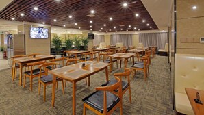 A hotel conference room with multiple tables and chairs, a television screen, and a wooden ceiling. - Days Hotel Zhangjiajie (Zhangjiajie)