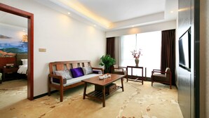 A hotel room with a sofa, a coffee table, a TV, a window with curtains, and a plant. - Days Hotel Zhangjiajie (Zhangjiajie)