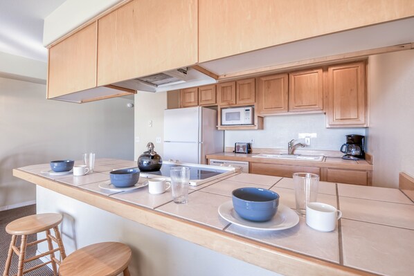 Una cocina moderna con armarios de madera, microondas, refrigerador y cafetera.