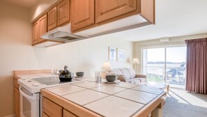 A modern kitchen with wooden cabinets, a built-in stove, and a large island with a sink.