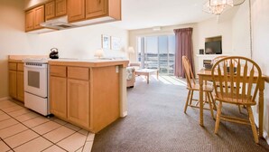 A kitchen with wooden cabinets, a stove, and a dining area with a table and chairs.