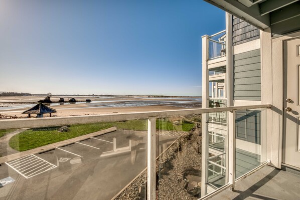 A view of a beachfront property with a parking lot, a gazebo, and a building with balconies overlooking the beach.