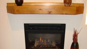 A fireplace with a mantel shelf holding two vases, a rug, and a vase with dried plants. - Tierra Del Sol 1 by MoabCondos4Rent (Moab)