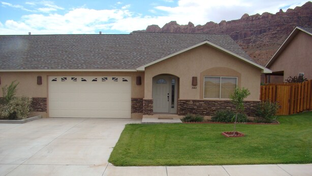 A single-story house with a garage, stone accents, and a well-maintained lawn. - Tierra Del Sol 1 by MoabCondos4Rent (Moab)