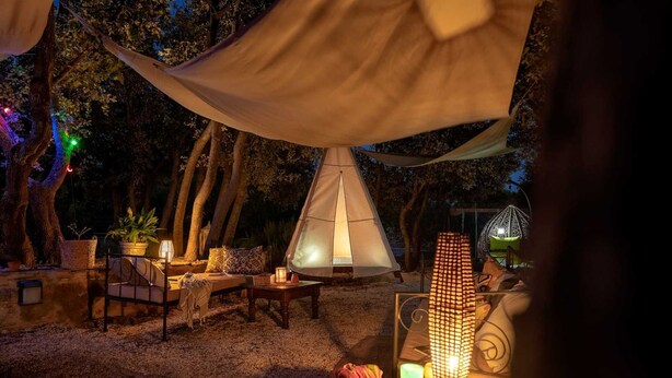 A tented outdoor area with a table, chairs, and a hanging lantern.