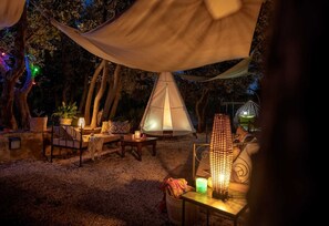A tented outdoor area with a table, chairs, and a hanging lantern.