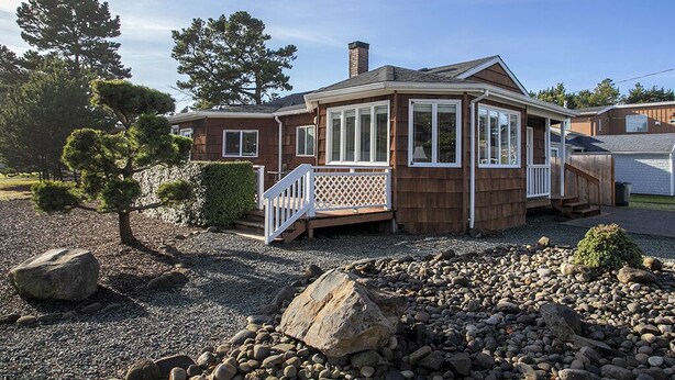 Une maison à deux étages avec un porche couvert, une cheminée et une allée gravillonnée.